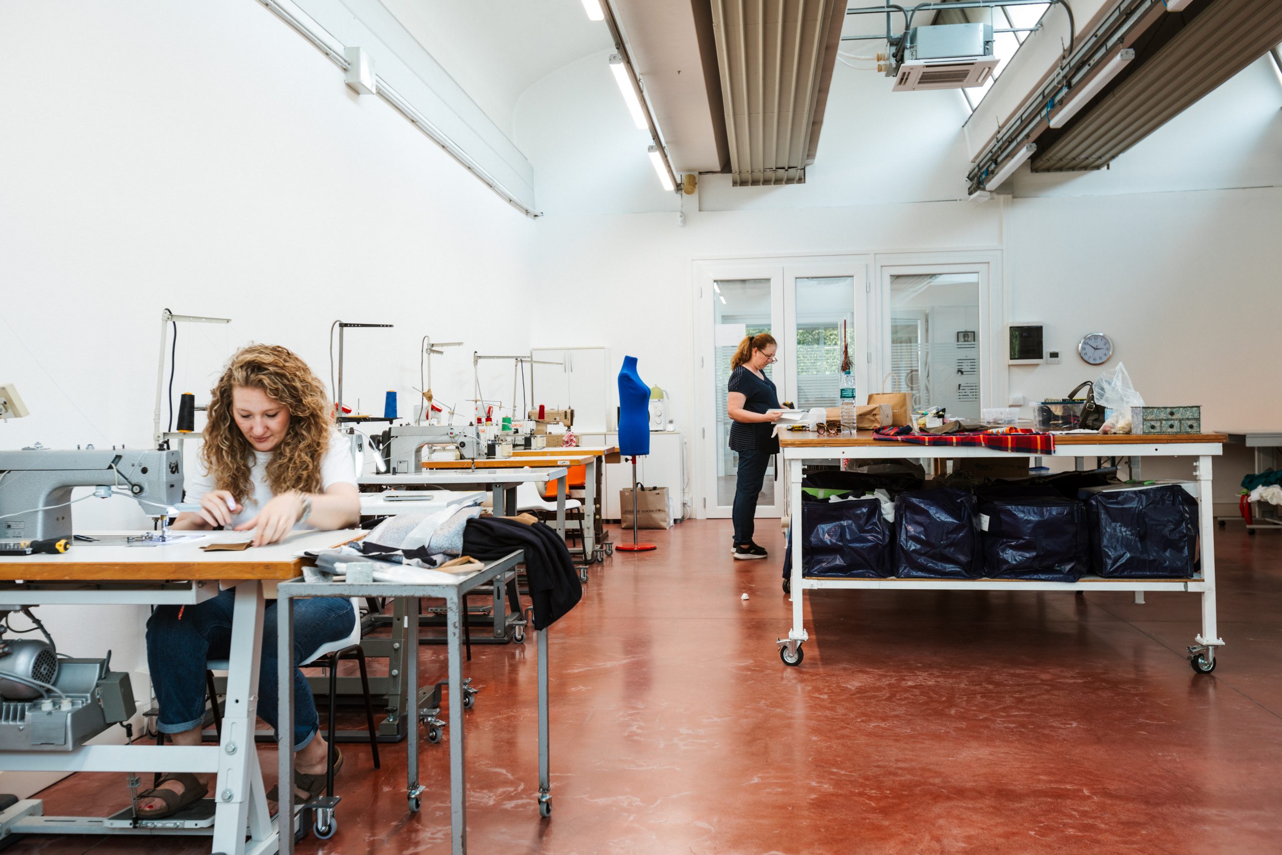 Chiara e Cristina al lavoro tra le macchine della sartoria